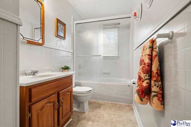 full bathroom with tile patterned floors, toilet, tile walls, vanity, and shower / washtub combination