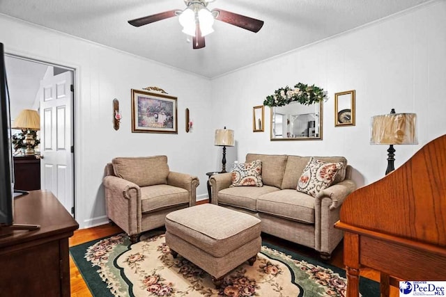 living room with hardwood / wood-style flooring, ceiling fan, and ornamental molding