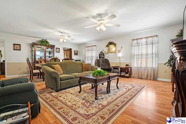 living room with hardwood / wood-style floors, a textured ceiling, and ceiling fan