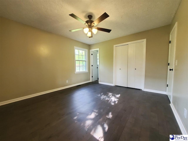 unfurnished bedroom featuring dark wood-type flooring, a closet, baseboards, and a textured ceiling