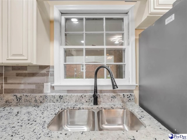 1341 Marshall Ave, Florence, SC 29501 - kitchen view of a sink, tasteful backsplash, light stone countertops, white cabinets, and freestanding refrigerator