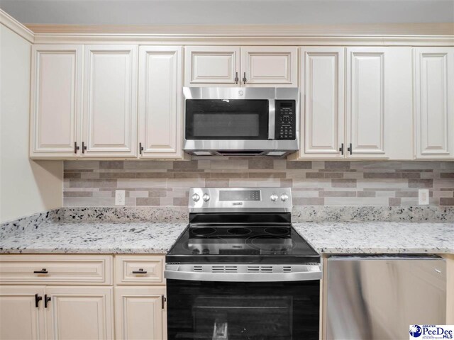 1341 Marshall Ave, Florence, SC 29501 - kitchen featuring appliances with stainless steel finishes, tasteful backsplash, light stone counters, and cream cabinets