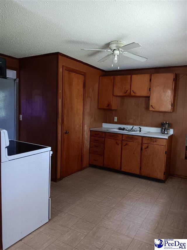 702 New Hampton Rd, Hartsville, SC 29550 - kitchen with white range with electric stovetop, brown cabinetry, light countertops, freestanding refrigerator, and a textured ceiling