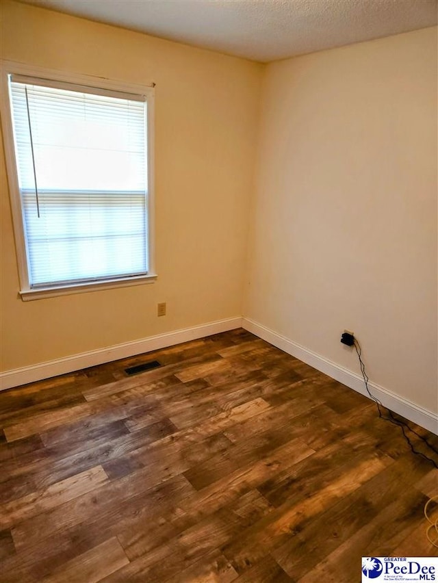 empty room featuring dark wood-type flooring and a textured ceiling