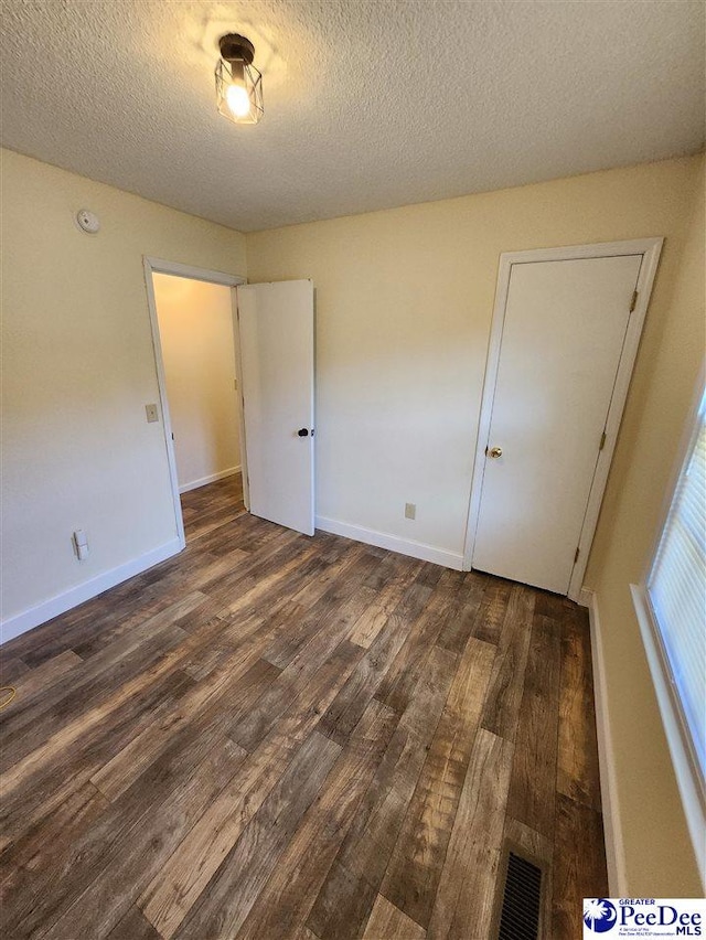 unfurnished bedroom featuring dark hardwood / wood-style floors and a textured ceiling