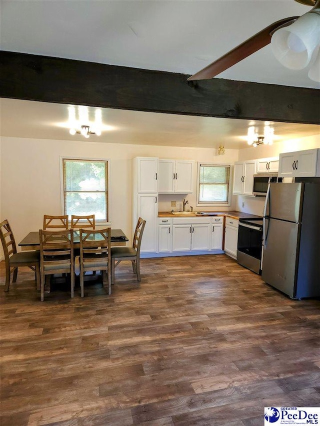 kitchen with stainless steel appliances, white cabinets, dark hardwood / wood-style flooring, and beamed ceiling