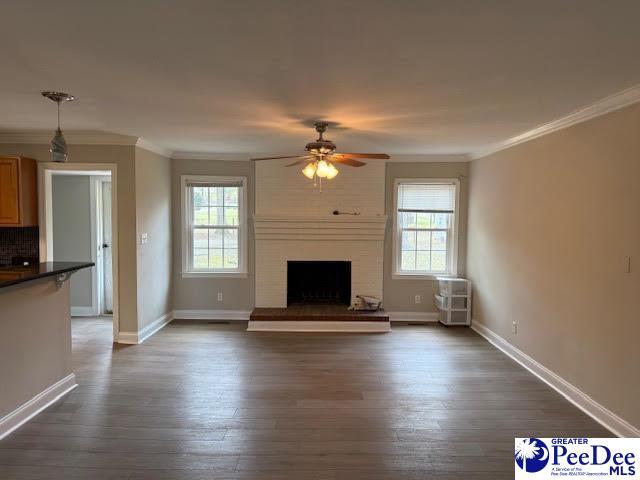 270 Quinby Cir, Quinby, SC 29506 - unfurnished living room featuring crown molding, ceiling fan, baseboards, and dark wood-style flooring