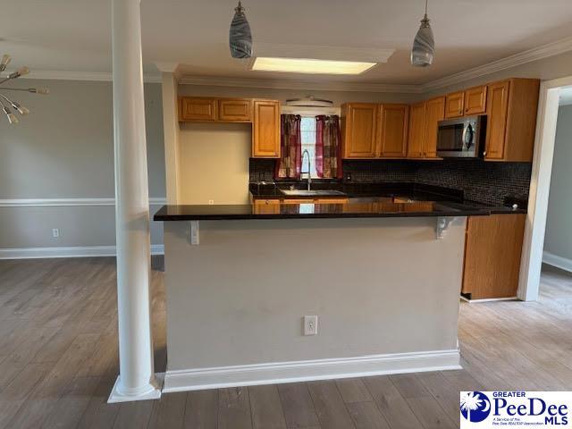 270 Quinby Cir, Quinby, SC 29506 - kitchen with a sink, decorative columns, dark countertops, crown molding, and stainless steel microwave
