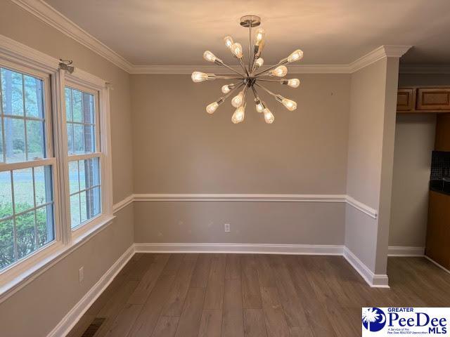 270 Quinby Cir, Quinby, SC 29506 - unfurnished dining area featuring a notable chandelier, baseboards, ornamental molding, and dark wood-style floors