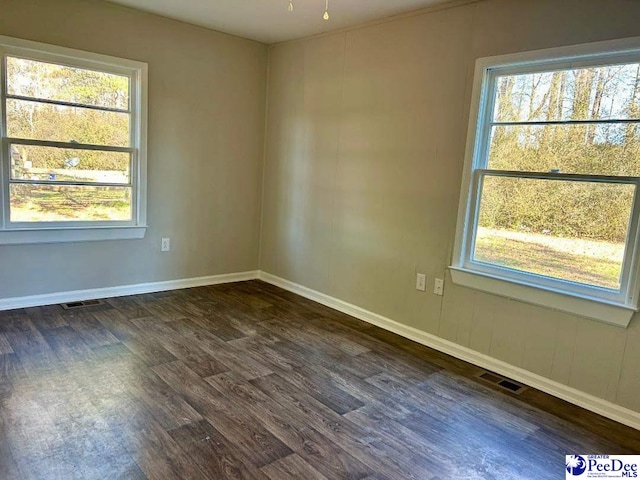 unfurnished room with plenty of natural light and dark hardwood / wood-style floors