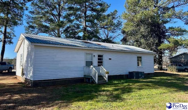 rear view of property featuring a yard and central air condition unit