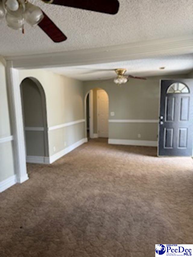 carpeted spare room featuring ceiling fan and a textured ceiling