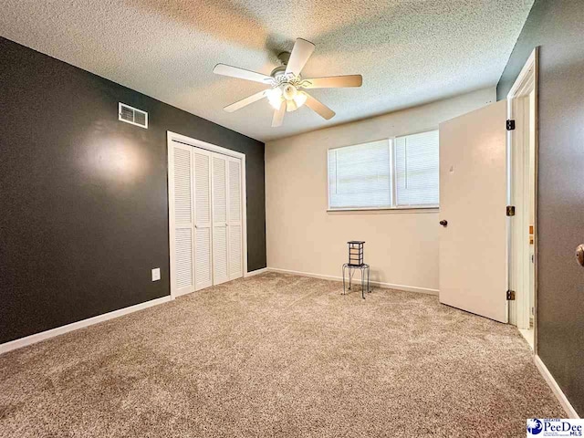 unfurnished bedroom with ceiling fan, light carpet, a closet, and a textured ceiling