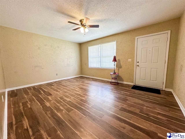 empty room with ceiling fan, dark hardwood / wood-style floors, and a textured ceiling