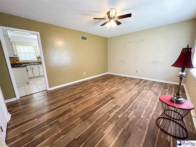 unfurnished living room with ceiling fan, light hardwood / wood-style floors, and a textured ceiling