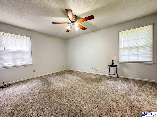 spare room with ceiling fan, carpet floors, a textured ceiling, and a wealth of natural light