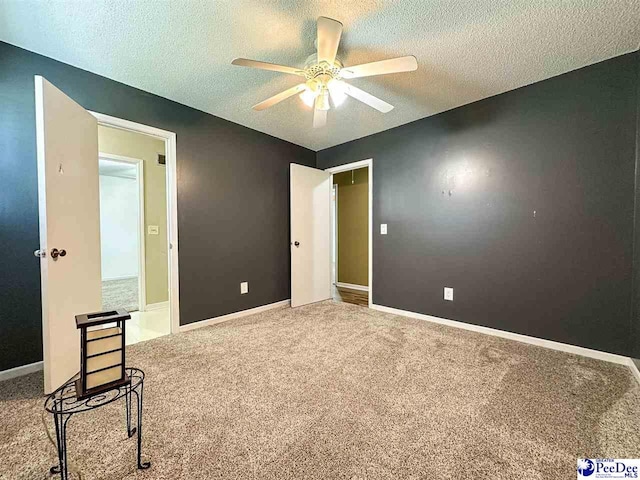 interior space featuring ceiling fan, carpet floors, and a textured ceiling