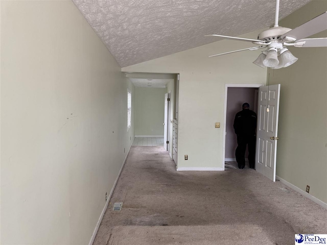 interior space with light carpet, baseboards, vaulted ceiling, and a textured ceiling