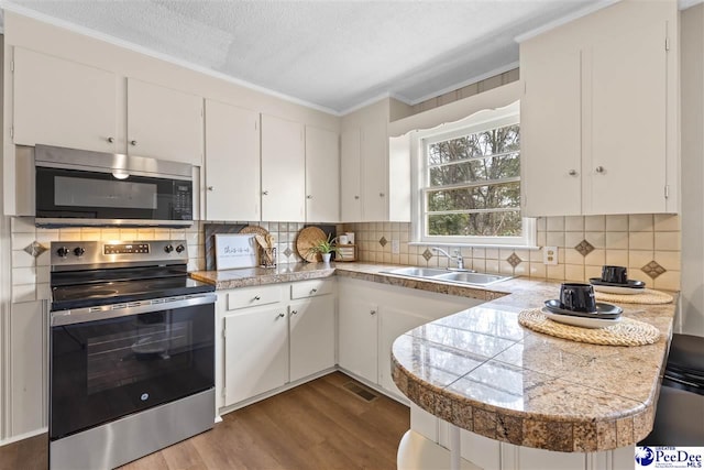 kitchen with stainless steel appliances, white cabinetry, sink, and light hardwood / wood-style flooring