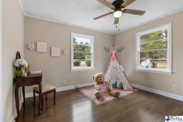 rec room with dark hardwood / wood-style flooring, ceiling fan, crown molding, and a textured ceiling