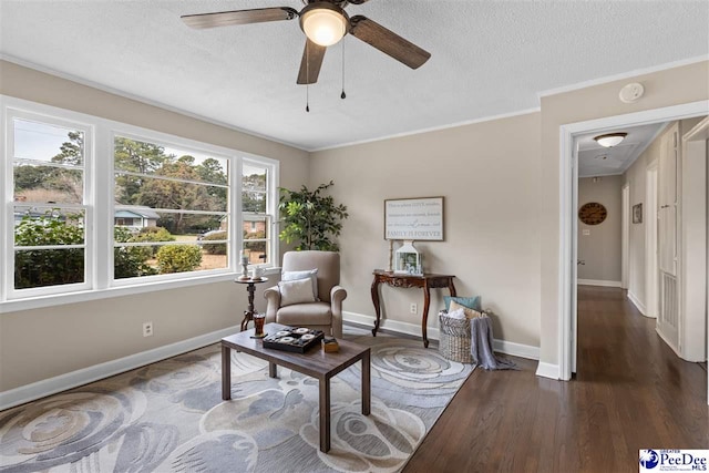 living area with crown molding, ceiling fan, dark hardwood / wood-style floors, and a textured ceiling