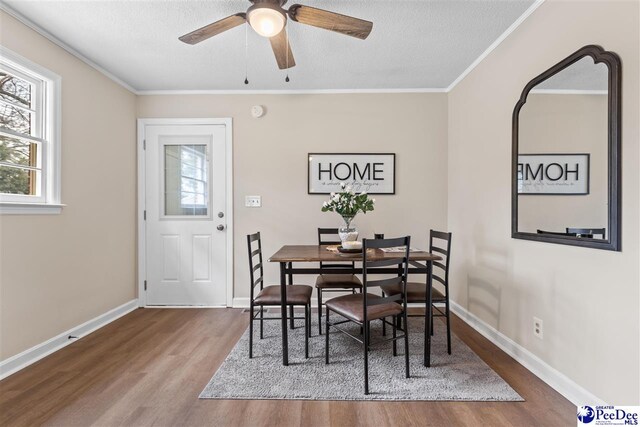 dining area featuring hardwood / wood-style flooring, ceiling fan, ornamental molding, and a textured ceiling