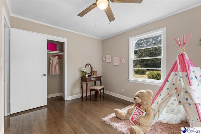 rec room featuring ornamental molding, dark wood-type flooring, and ceiling fan