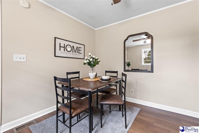 dining room with crown molding, ceiling fan, dark hardwood / wood-style floors, and a textured ceiling