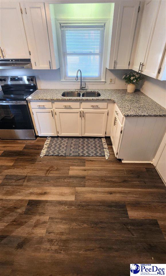 kitchen with sink, white cabinetry, stainless steel electric range, dark hardwood / wood-style floors, and light stone countertops