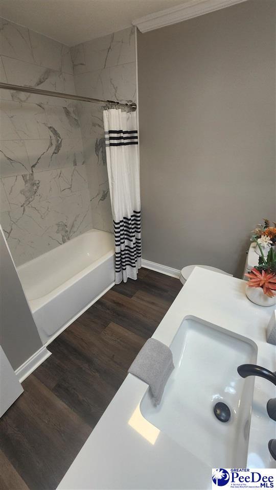 bathroom with hardwood / wood-style floors, crown molding, and shower / bath combo