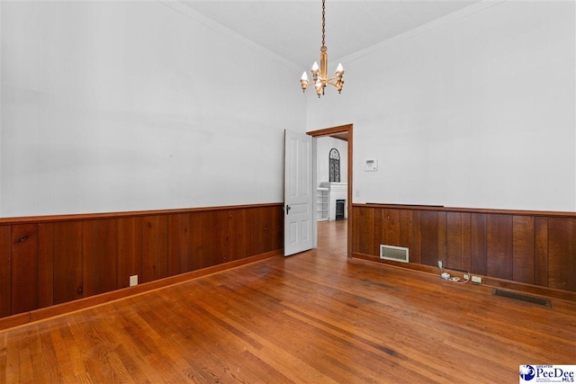 118 Ford Ave, Mullins, SC 29574 - unfurnished room featuring a chandelier, wood finished floors, wainscoting, ornamental molding, and wood walls