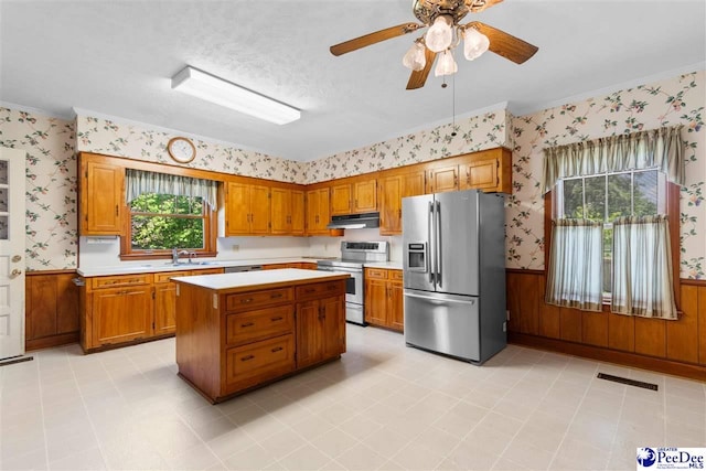 118 Ford Ave, Mullins, SC 29574 - kitchen with appliances with stainless steel finishes, wallpapered walls, wainscoting, light countertops, and brown cabinetry
