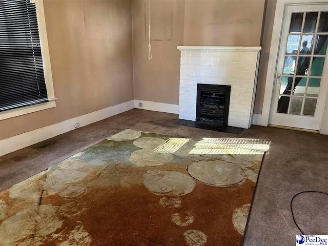 unfurnished living room featuring dark carpet and a brick fireplace