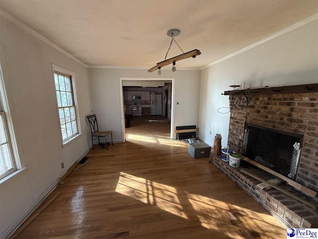 unfurnished living room featuring ornamental molding, wood-type flooring, a fireplace, and a textured ceiling