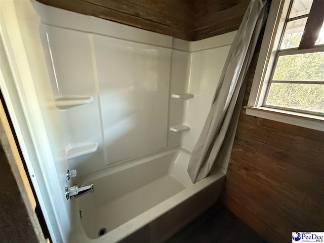 bathroom featuring shower / tub combo and wood walls