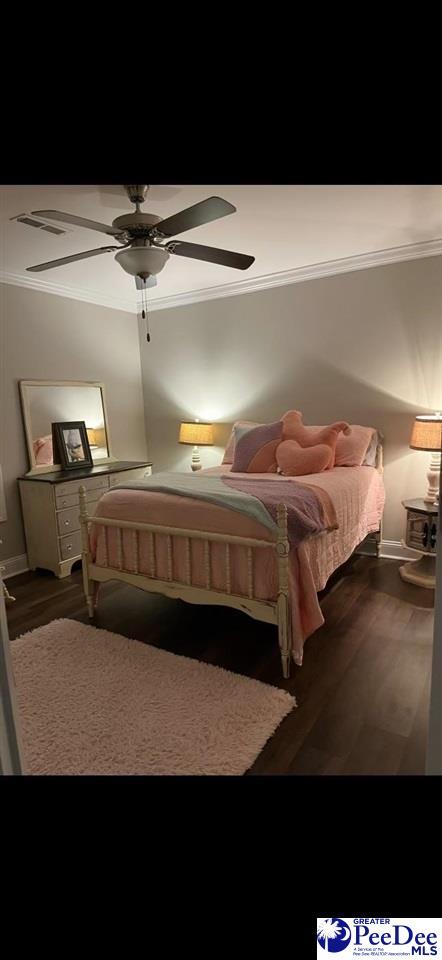 bedroom with crown molding, wood-type flooring, and ceiling fan