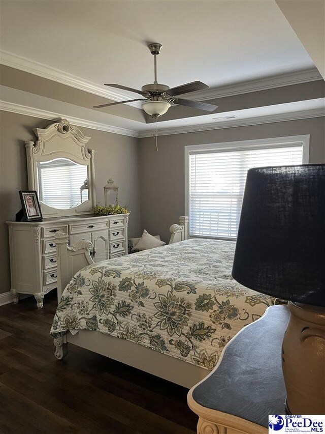 bedroom with ornamental molding, ceiling fan, dark hardwood / wood-style flooring, and a tray ceiling