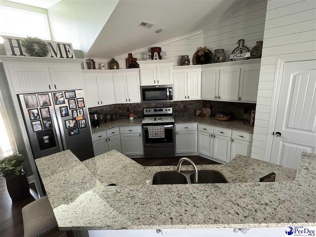 kitchen with appliances with stainless steel finishes, sink, white cabinets, and light stone counters