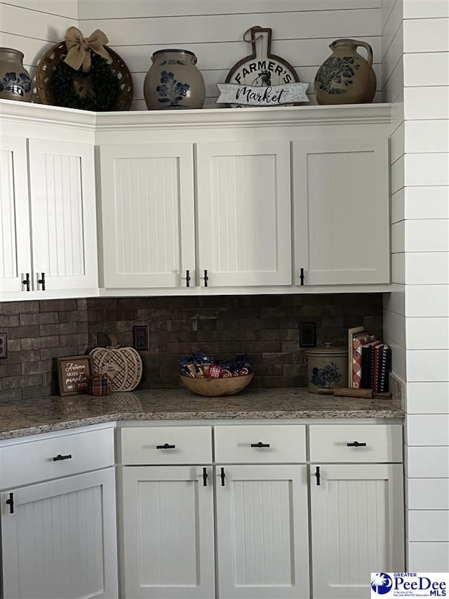 bar featuring white cabinetry, tasteful backsplash, and stone countertops