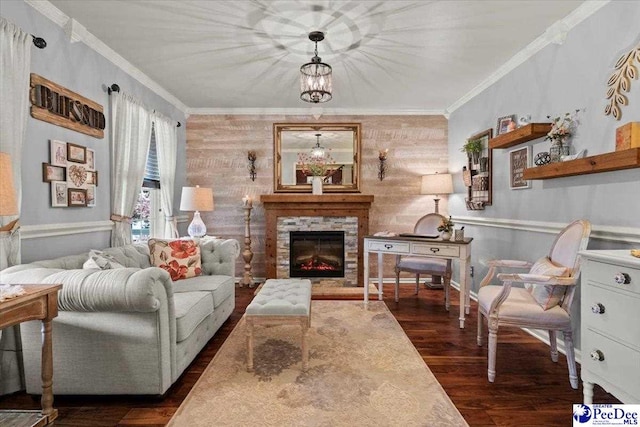living room featuring crown molding, dark wood finished floors, a stone fireplace, and a chandelier