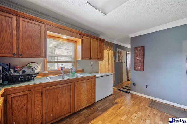 903 N Park St, Mullins, SC 29574 - kitchen with crown molding, brown cabinetry, light wood-style flooring, a textured ceiling, and fridge
