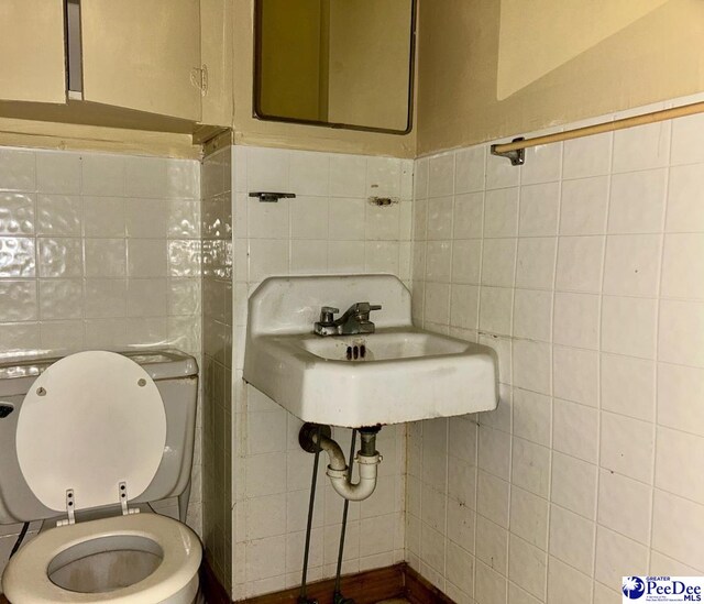 bathroom featuring toilet and tile walls