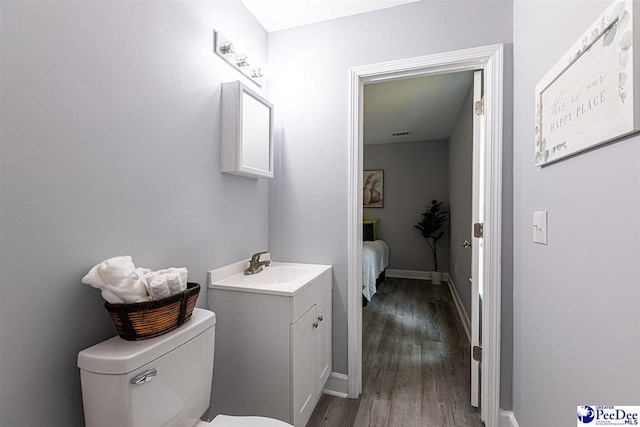 bathroom with hardwood / wood-style flooring, vanity, and toilet