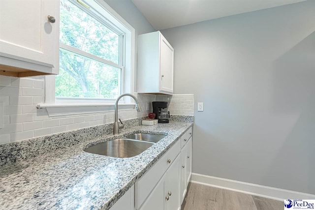 kitchen with sink, white cabinets, light stone counters, and decorative backsplash