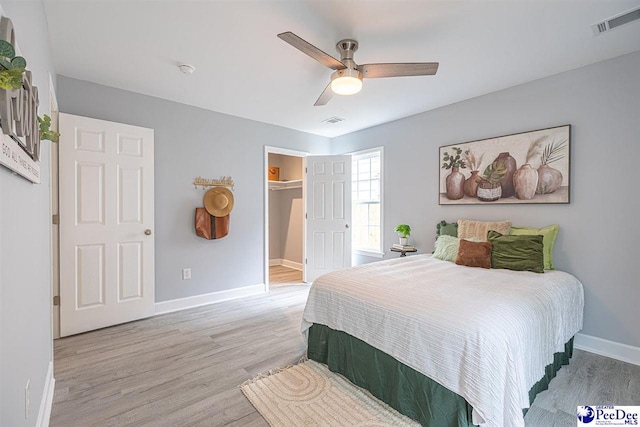 bedroom with ceiling fan, a spacious closet, a closet, and light wood-type flooring