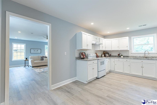 kitchen featuring light stone counters, sink, white electric stove, and white cabinets