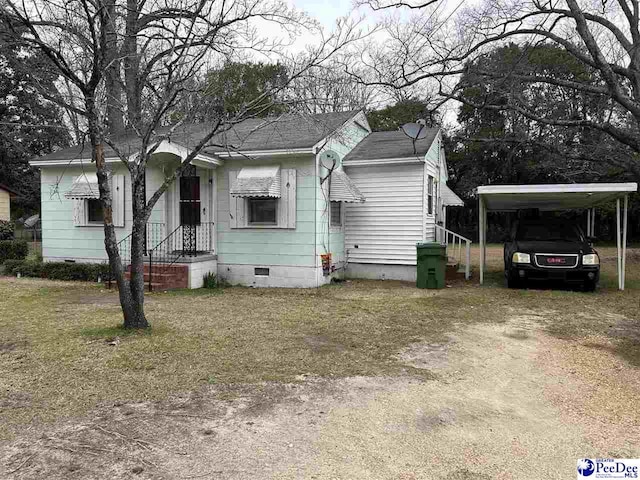 bungalow-style home with crawl space, a carport, roof with shingles, and dirt driveway