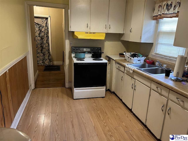 kitchen with light wood-style flooring, electric range oven, light countertops, white cabinets, and under cabinet range hood