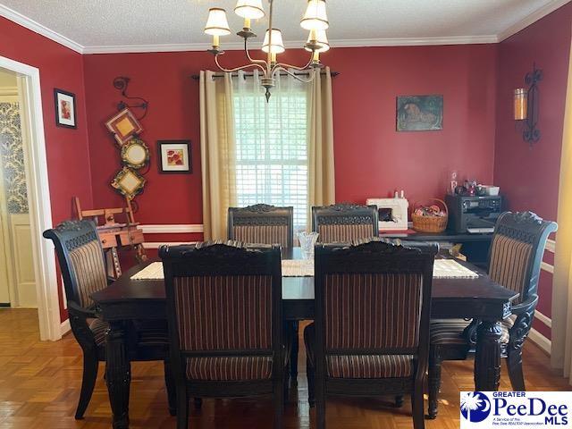 dining space featuring an inviting chandelier, parquet flooring, ornamental molding, and a textured ceiling