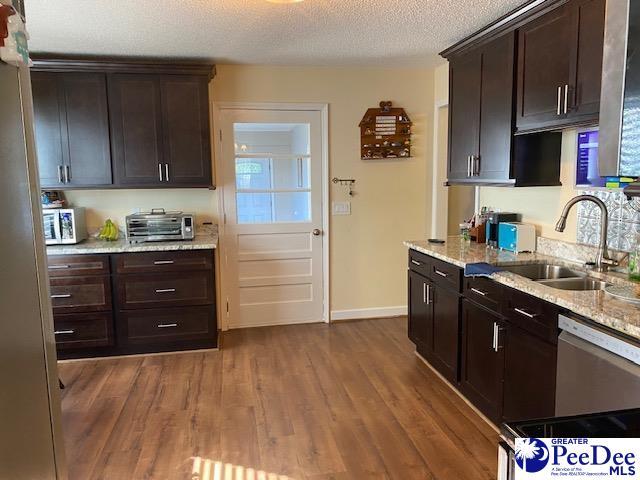 kitchen featuring wood-type flooring, white dishwasher, sink, and dark brown cabinets